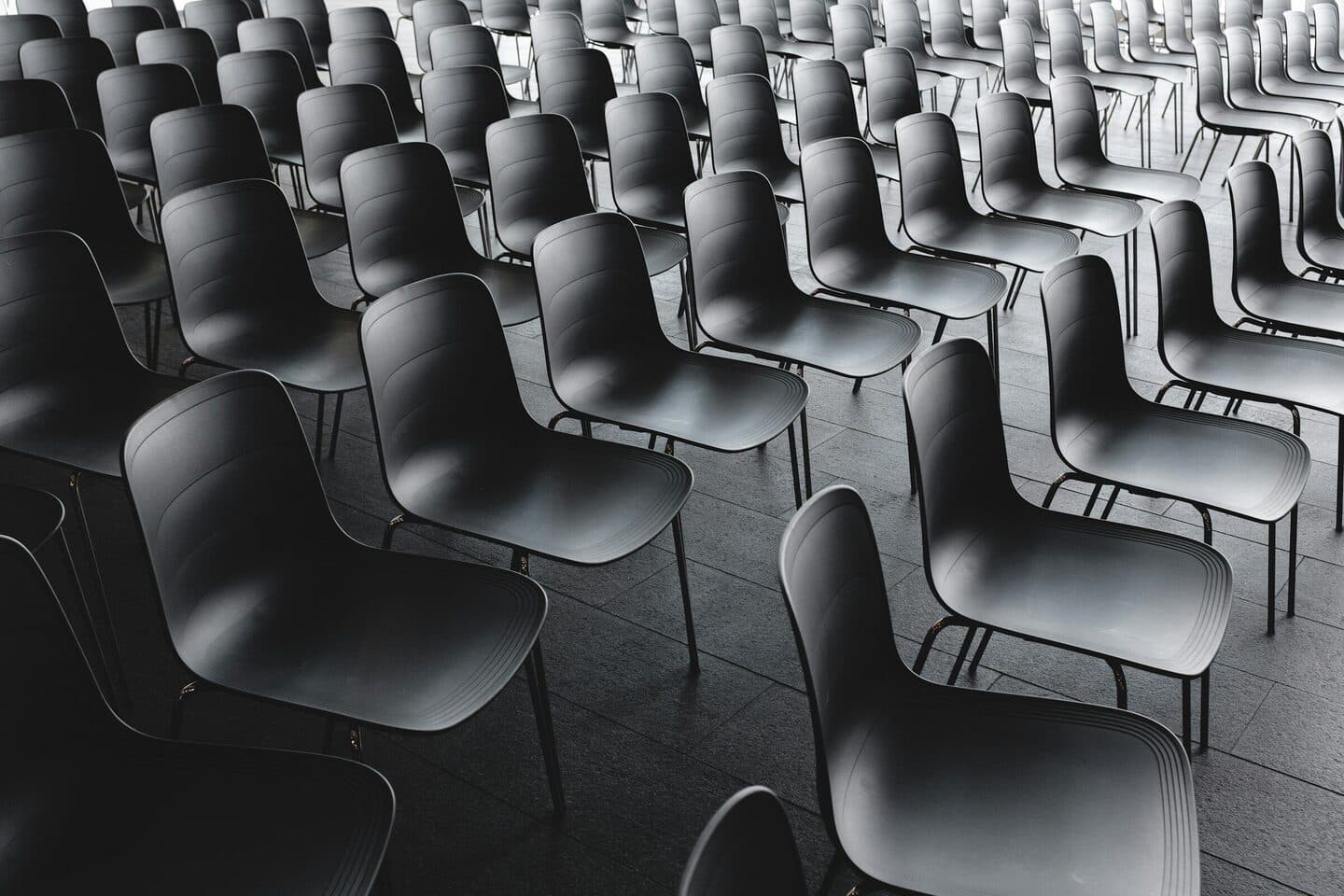 Empty rows of chairs in an event hall, black and white