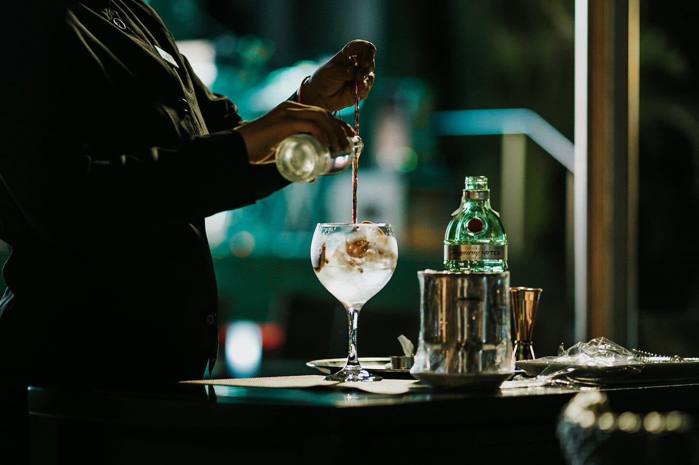 Bartender pours a drink into a wine glass with ice