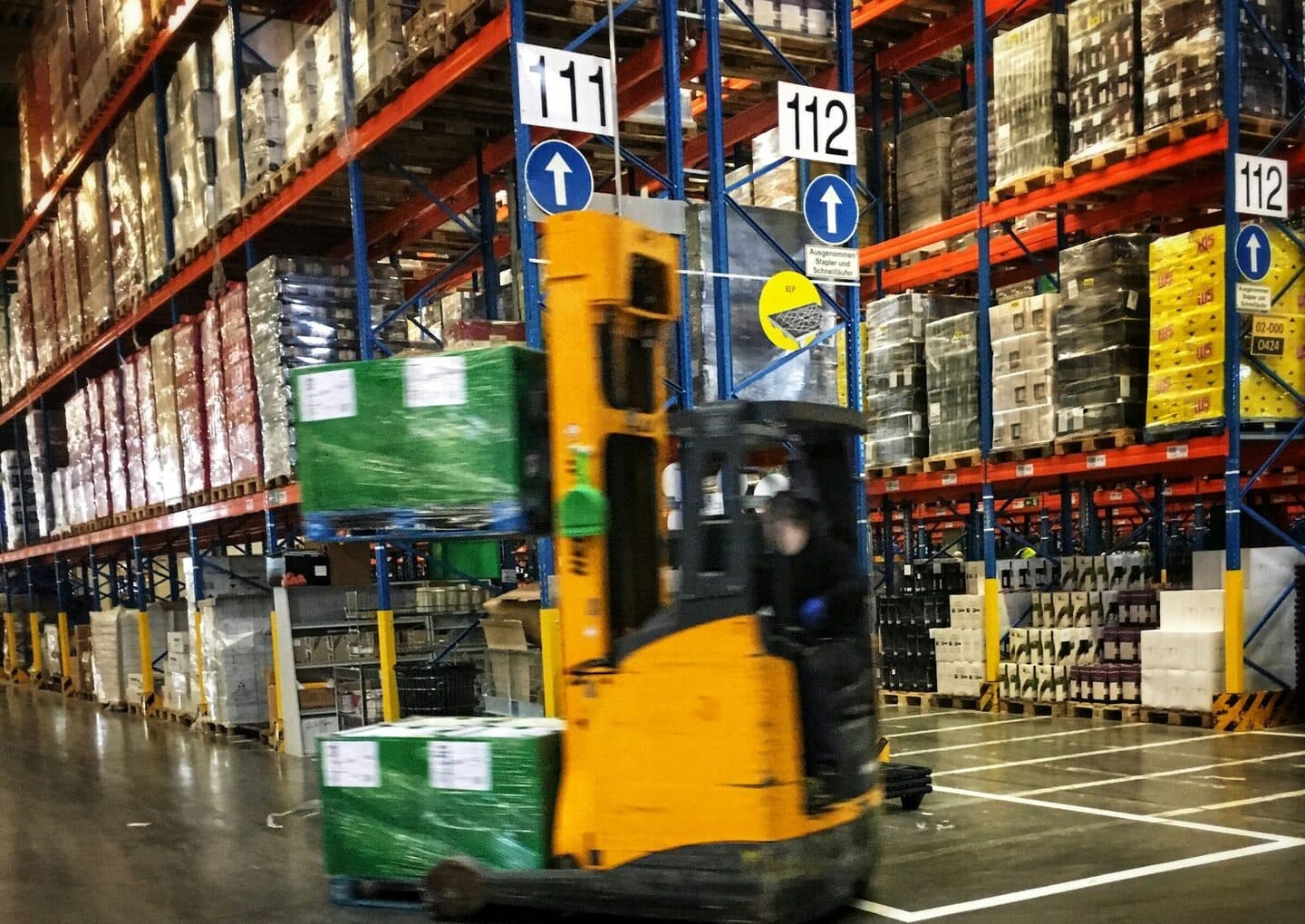 Forklift drives through the aisles of a high-bay warehouse