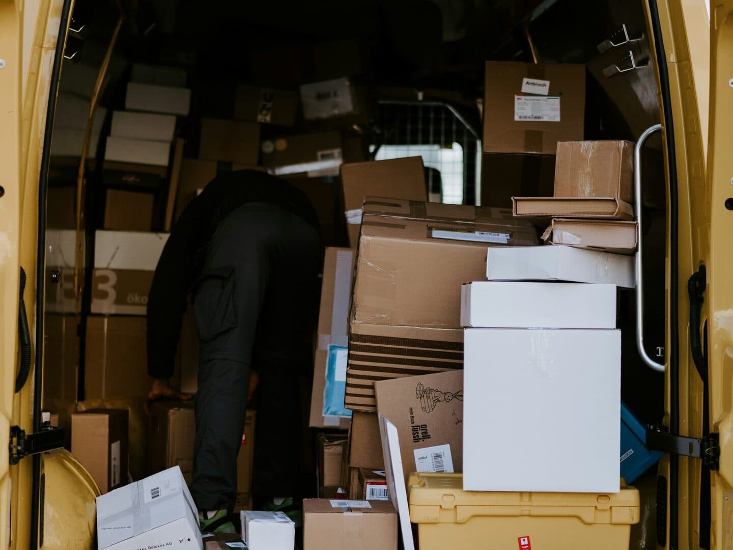 View into an open van full of parcels, with a person sorting the load inside
